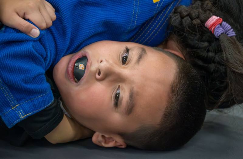 Kid with a mouthguard catching his breath on the mat