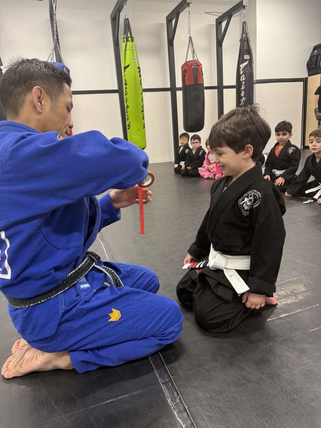 Coach adding a stripe to a kid's white belt
